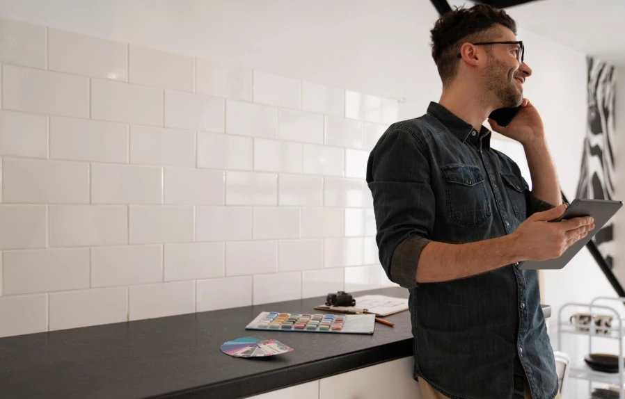 Contractor on a phone call with tile and paint samples on a kitchen counter