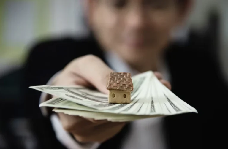 Property owner holding cash and a small model house representing monthly rental payments