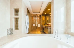 Soaking tub with marble walls, built in niches and glass shower doors showing luxury master bathroom remodel ideas in Los Angeles