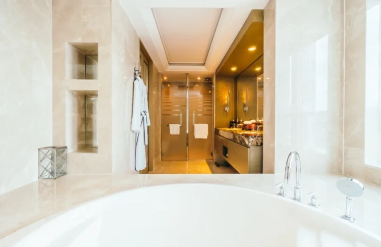 Soaking tub with marble walls, built in niches and glass shower doors showing luxury master bathroom remodel ideas in Los Angeles